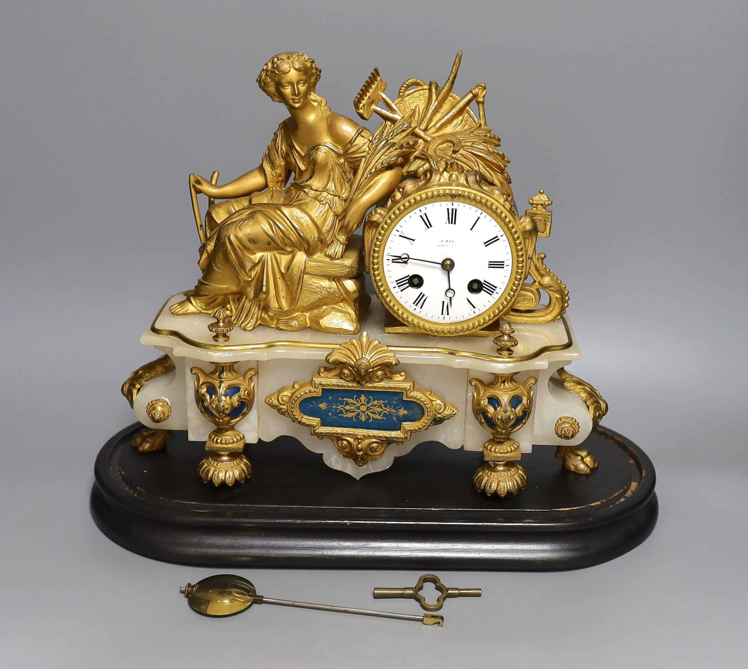 A 19th century French gilt metal and alabaster figural mantle clock with key and pendulum